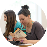 A female student sits at her desk reading a book.